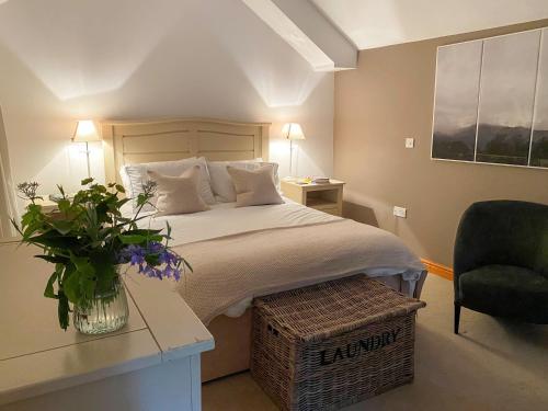 a bedroom with a bed and a chair and a table at Dove Holme Cottage in Grasmere