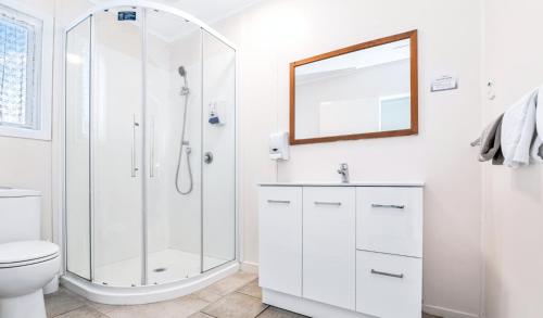 a white bathroom with a shower and a toilet at Kowhai Motel Rotorua in Rotorua