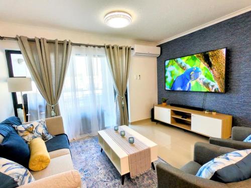 een woonkamer met een bank en een flatscreen-tv bij Pristine King Size Bed Apartment In Secure Complex in Durban