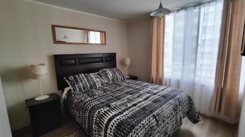 1 dormitorio con cama con edredón y ventana en Departamento 1B+1D Álvarez 1802, en Viña del Mar