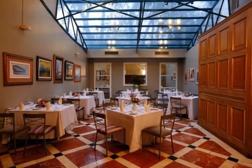 een restaurant met witte tafels en stoelen en een glazen plafond bij Suites del Bosque Hotel in Lima