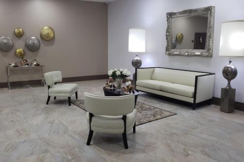 sala de estar con sofá, sillas y espejo en Habitacion Matrimonial Vista Rio junto Wyndham, en Guayaquil