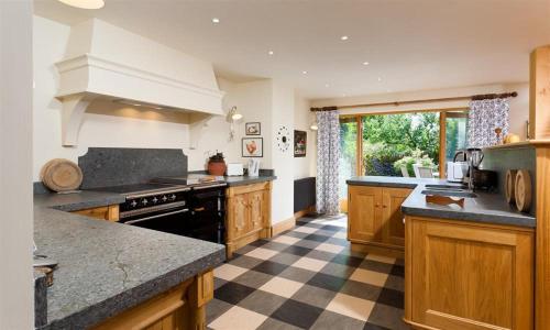 a large kitchen with wooden cabinets and a checkered floor at The Old Coach House in Troutbeck