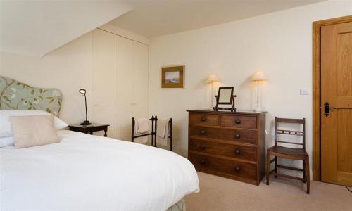 a bedroom with a white bed and a wooden dresser at The Old Coach House in Troutbeck