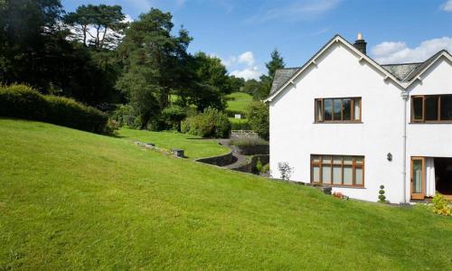 a white house on top of a green hill at The Old Coach House in Troutbeck