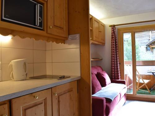 une cuisine avec un four micro-ondes et un canapé dans une chambre dans l'établissement Studio rénové au pied des pistes, balcon sud, 3 pers., Méribel - FR-1-180-32, à Méribel