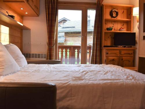une chambre avec un grand lit et une grande fenêtre dans l'établissement Charmant Studio rénové, balcon Sud, à 50m des pistes - Méribel - FR-1-180-35, à Méribel