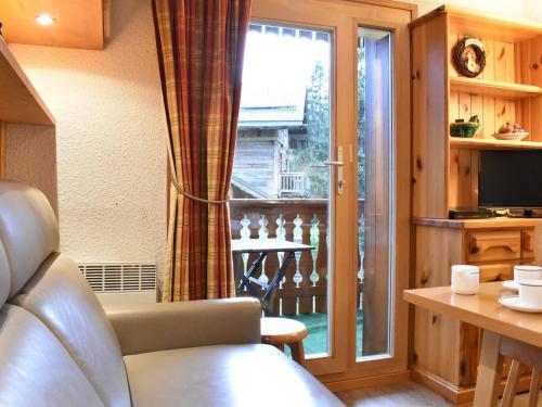 un salon avec un canapé et une porte coulissante en verre dans l'établissement Charmant Studio rénové, balcon Sud, à 50m des pistes - Méribel - FR-1-180-35, à Méribel
