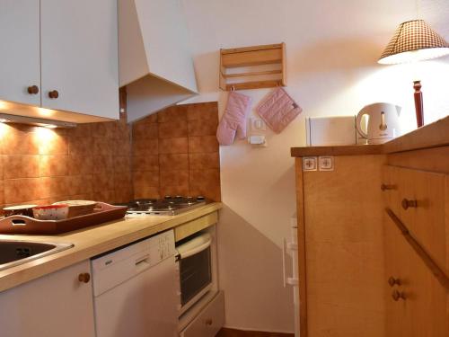 une cuisine avec des armoires blanches et un four à plaques de cuisson dans l'établissement Meribel : Bel Appartement 2 Pièces avec Parking, Proche Pistes et Commerces - FR-1-180-89, à Méribel
