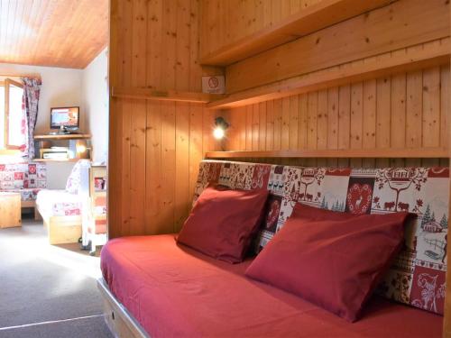 - une chambre dotée d'un lit avec des draps rouges et des murs en bois dans l'établissement Appartement cosy 2P à Méribel, 5 pers, proche pistes et commerces, parking inclus - FR-1-180-92, à Méribel