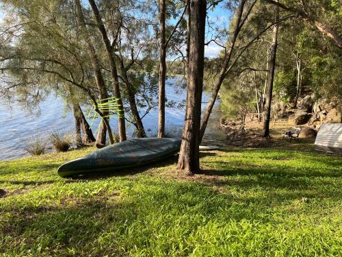 a green canoe sitting on the grass near the water at The downstairs delight 2brm , 6+ guests & dogs ok in Lake Munmorah
