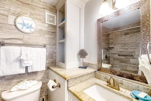 a bathroom with a sink and a toilet and a mirror at Top of the Gulf 702 Teal Waters in Panama City Beach