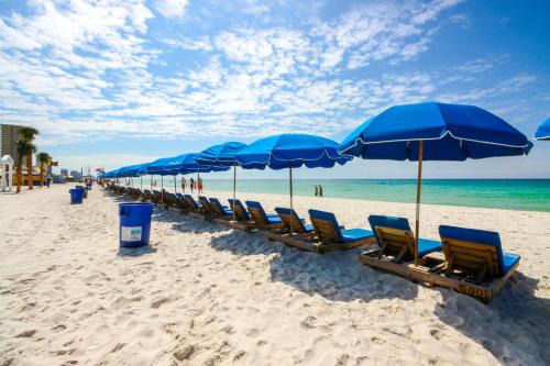 a row of blue umbrellas and chairs on a beach at Top of the Gulf 702 Teal Waters in Panama City Beach