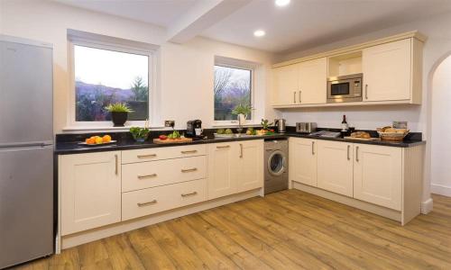 a large kitchen with white cabinets and a dishwasher at Lanterns At Grasmere in Grasmere