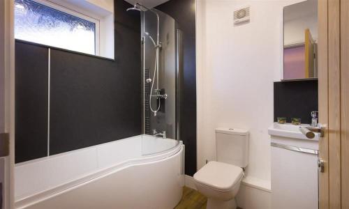 a bathroom with a tub and a toilet and a window at Lanterns At Grasmere in Grasmere