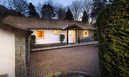 a small white house with a brick driveway at Lanterns At Grasmere in Grasmere
