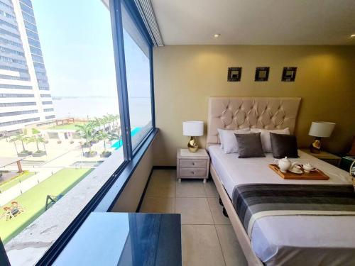 1 dormitorio con cama grande y ventana grande en Ecusuites Bellini 404 King RiverView AirportGye, en Guayaquil