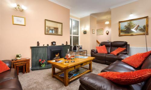 a living room with leather furniture and a fireplace at Fairhaven in Bowness-on-Windermere
