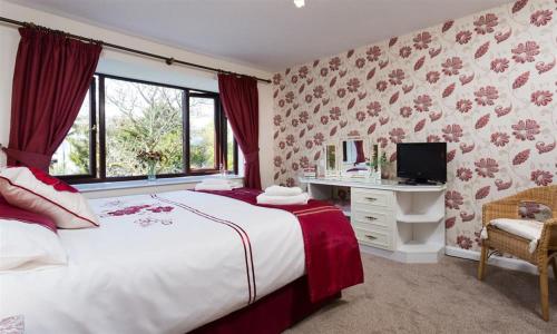 a bedroom with a bed and a desk and a television at Fairhaven in Bowness-on-Windermere