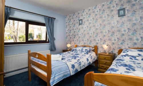 1 dormitorio con 2 camas y ventana en Fairhaven, en Bowness-on-Windermere
