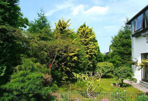 a garden with trees and bushes and a house at Fairhaven in Bowness-on-Windermere