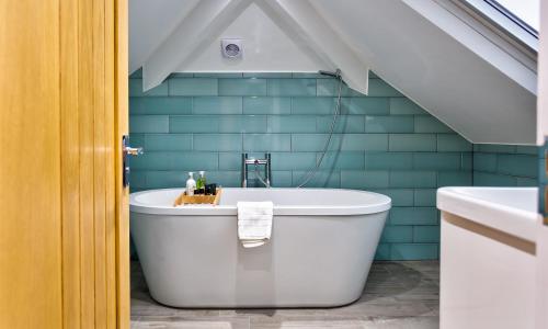 a bathroom with a white tub and blue tiles at Wynford in Ambleside