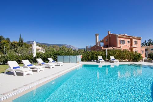 a swimming pool with lounge chairs and a house at VILLA ALEXANDRA in Dassia