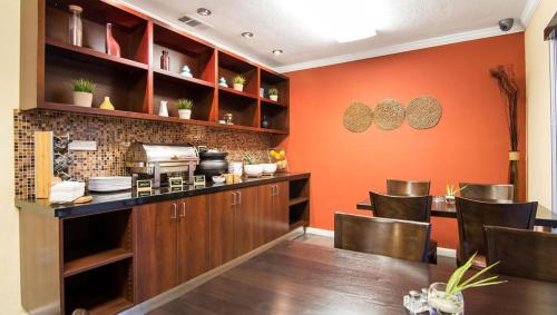 a kitchen with orange walls and a counter with chairs at The Zen Hotel Palo Alto in Palo Alto
