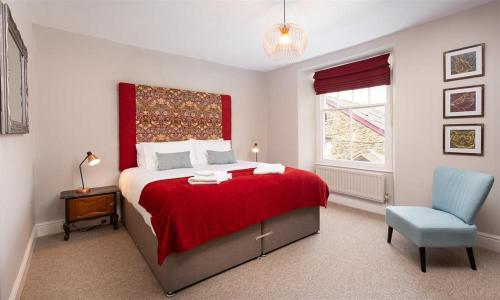 ウィンダミアにあるBellflower Cottageのベッドルーム(赤いベッド1台、青い椅子付)