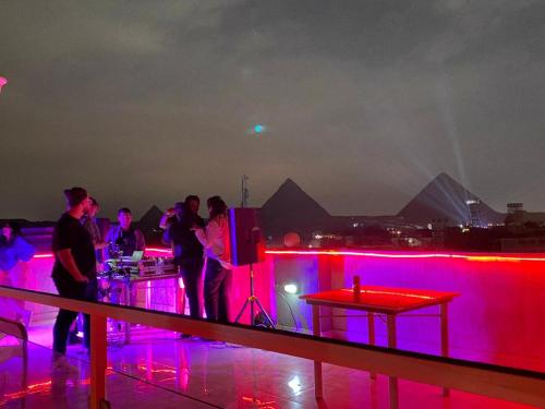 un groupe de personnes debout sur un toit la nuit dans l'établissement Khufu Pyramids Hotel, au Caire