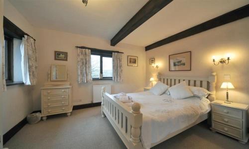 una camera da letto con un grande letto bianco e una finestra di Butt Hill Cottage a Troutbeck