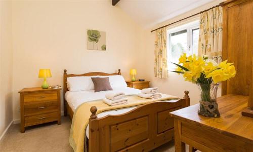 a bedroom with a bed and a vase of yellow flowers at Riverside Cottages No 2 in Ambleside