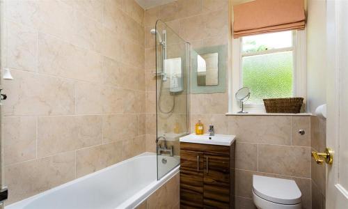 a bathroom with a tub and a toilet and a sink at Highbank in Bowness-on-Windermere