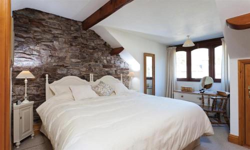 una camera da letto con un grande letto bianco e un muro di pietra di High Raise a Grasmere