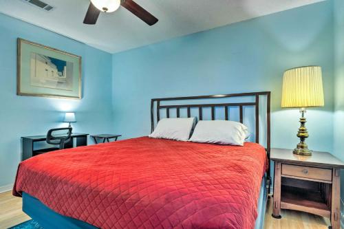 a bedroom with a red bed and a table with a lamp at Cute Pensacola Townhome about 9 Mi to Downtown! in Pensacola