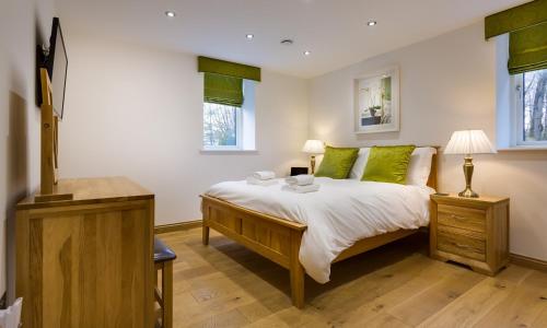 Un dormitorio con una cama grande con almohadas verdes. en Tall Trees, en Bowness-on-Windermere