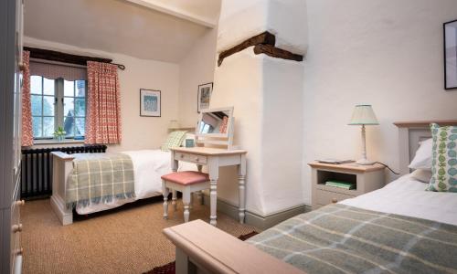 a bedroom with two beds and a desk in it at Stone Arthur Cottage in Grasmere