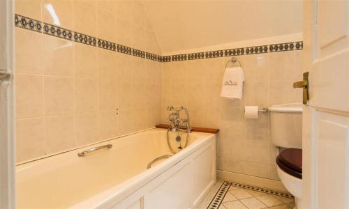 a bathroom with a bath tub and a toilet at Priory Lodge in Windermere