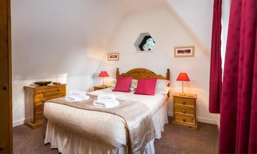 a bedroom with a large bed with red pillows at Priory Lodge in Windermere