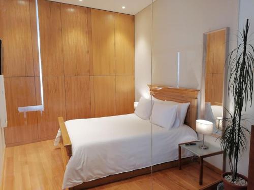 ein Schlafzimmer mit einem weißen Bett und einer Topfpflanze in der Unterkunft Garrett Houses in Póvoa de Varzim