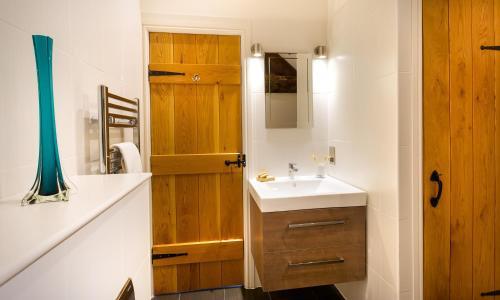 a bathroom with a sink and a wooden door at Church View At Troutbeck in Windermere