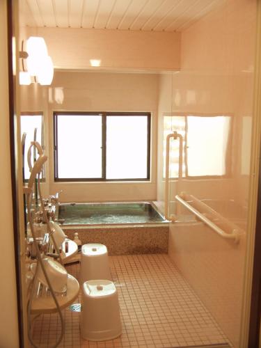 y baño con bañera, aseo y lavamanos. en Oyado Raku, en Takayama