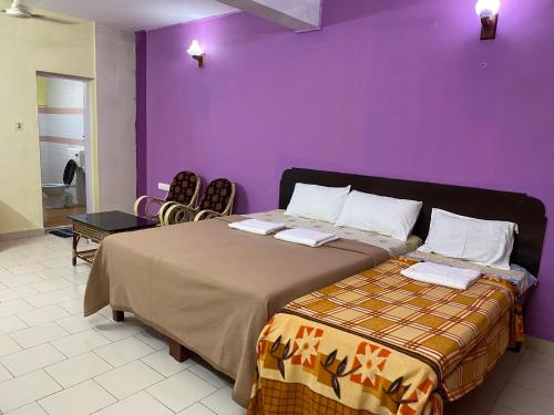 - une chambre avec des murs violets, un lit et des chaises dans l'établissement Hotel Samudra Tara, à Kovalam