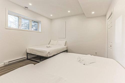 1 dormitorio blanco con 2 camas y ventana en Cheerful 4 bedroom home with inground heated pool, en Prévost