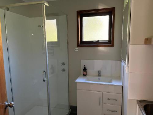 y baño con ducha y lavamanos. en Black Bream Point Cabins en Narooma