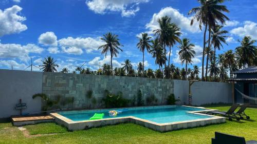 uma piscina num quintal com palmeiras em Village dos Coqueirais em São Miguel do Gostoso