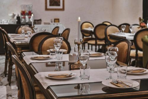 un comedor con mesas y sillas con gafas. en Garni hotel BARUT, en Šabac