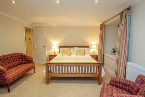 a bedroom with a bed and a couch and a chair at The Miller in Ambleside