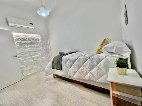 a white bedroom with a bed and a wine rack at Vivienda Casa Gabi in Úbeda