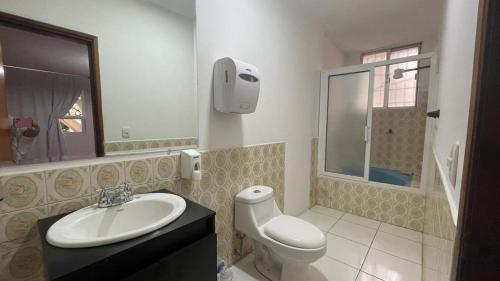 ein Badezimmer mit einem Waschbecken, einem WC und einem Spiegel in der Unterkunft Casa Lomas in Tegucigalpa